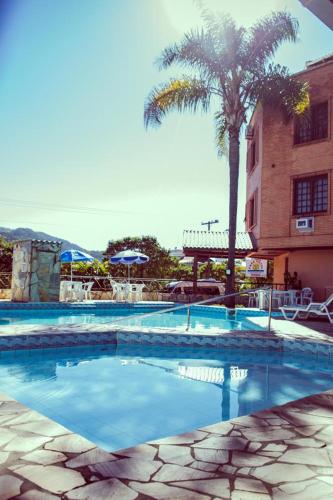 a swimming pool with a palm tree and a building at Termas Park Hotel in Gravatal
