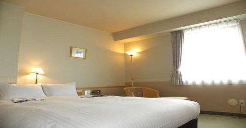 a bedroom with a large white bed with a window at Hotel Benex Yonezawa / Vacation STAY 14346 in Yonezawa