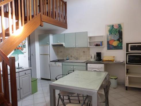 een keuken met witte kasten en een tafel. bij Villa avec piscine in Cap d'Agde