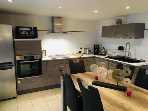 a kitchen with a wooden table and a kitchen with stainless steel appliances at Gîte de la Vallée in Dambach
