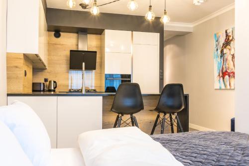 a bedroom with a bed and two chairs in front of a kitchen at Fabulous apartment in heart of Katowice in Katowice