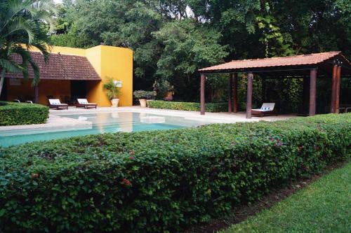 a swimming pool with a gazebo and a hedge at Hacienda Misne in Mérida