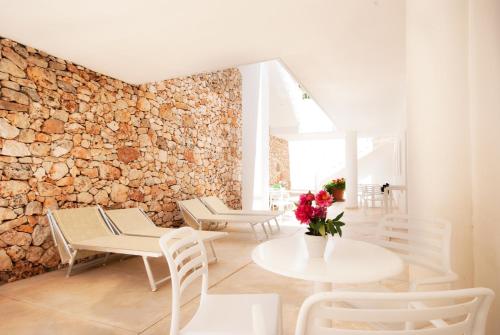 una stanza con tavoli e sedie e un muro in pietra di Hotel Beach Salento a Marina di Pescoluse