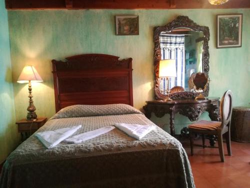 a bedroom with a bed and a mirror and a table at Posada San Sebastian in Antigua Guatemala