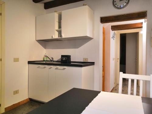 eine Küche mit weißen Schränken und einer Uhr an der Wand in der Unterkunft CASTELLO Ground Floor in Venedig