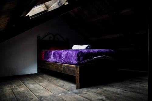 a bed with a purple comforter in a dark room at Casa Tequio in San Cristóbal de Las Casas