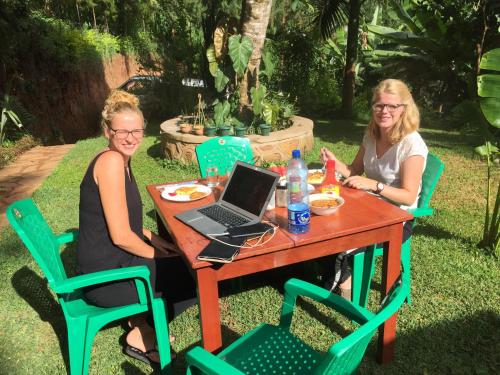 two women sitting at a table with a laptop at David Crater Homestay in Lushoto