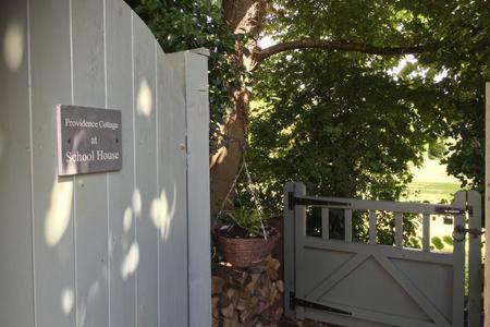 a house with a white gate and a tree at Providence Cottage a Sussex boutique retreat for two in Angmering
