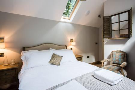 a bedroom with a large white bed and a chair at Providence Cottage a Sussex boutique retreat for two in Angmering