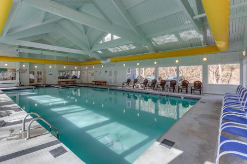 a large swimming pool with blue chairs in a building at Chalet High by Capital Vacations in Basye