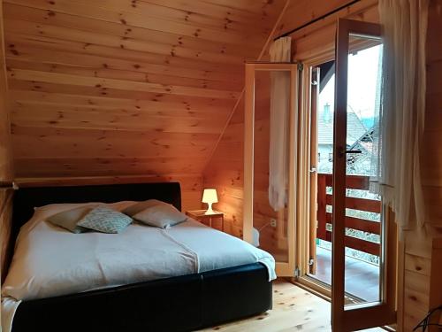 a bedroom with a bed with a wooden wall at Petit chalet Belosevic in Kuželj