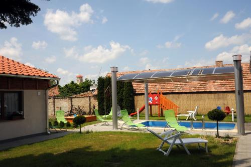 a backyard with a pool with green lawn chairs at Arany Szőlő Wellness Apartmanház in Hévíz