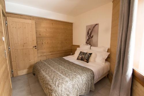 1 dormitorio con 1 cama con pared de madera en Le Bianca 102 Residence l'Epinette, en Valloire