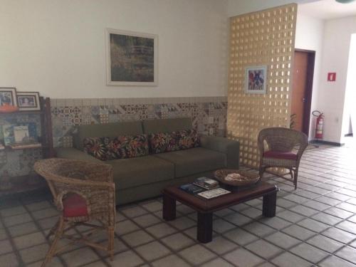 Una sala de estar con un sofá y dos sillas y una mesa. en Luz & Mar, en Aracaju