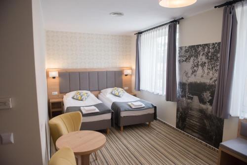 Cette chambre comprend 2 lits et une table. dans l'établissement Hotel Ossowski, à Swarzędz