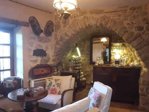 a living room with two white chairs and a stone wall at Chambre et Gite Le Roc sur l'Orbieu in Saint-Pierre-des-Champs