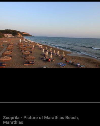 a beach with chairs and umbrellas and the ocean at Villa Thanos in Marathias