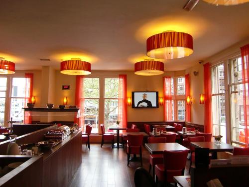 un restaurante con sillas rojas, mesas y ventanas en City Hotel, en Ámsterdam