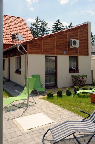 a house with a patio with green chairs in the yard at Arany Szőlő Wellness Apartmanház in Hévíz