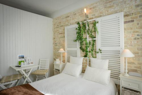 a bedroom with a white bed and a table and a desk at Logis Hôtel Restaurant l'Auberge Normande in Carentan