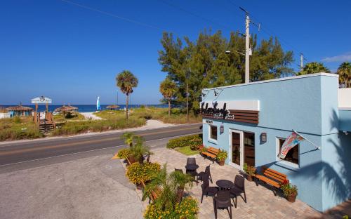 a blue building with tables and chairs next to a street at Silver Surf Gulf Beach Resort in Bradenton Beach
