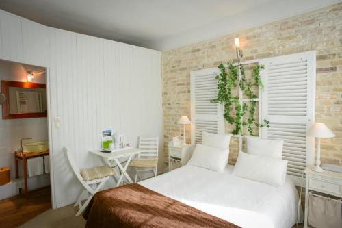 ein Schlafzimmer mit einem weißen Bett und einem Tisch mit einem Stuhl in der Unterkunft Auberge Normande in Carentan