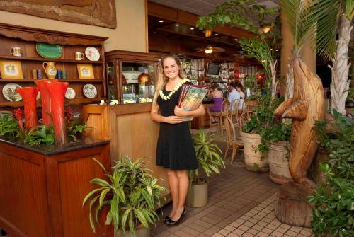 a woman standing in a store holding a book at Mana Kai Maui - Official Onsite Rental Company in Wailea