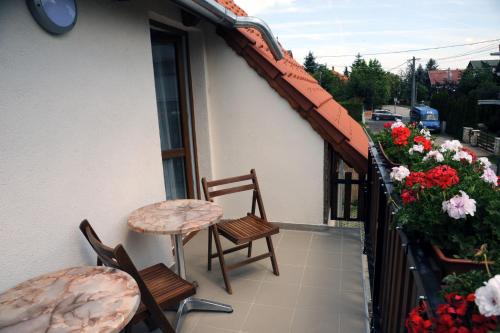 a balcony with two chairs and a table and flowers at Arany Szőlő Wellness Apartmanház in Hévíz