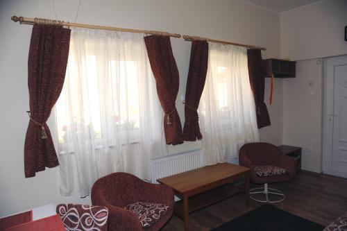 a room with two chairs and a table and windows at Arany Szőlő Wellness Apartmanház in Hévíz
