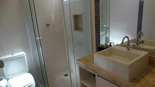 a white bathroom with a sink and a shower at Condomínio casa Juquehy in Juquei