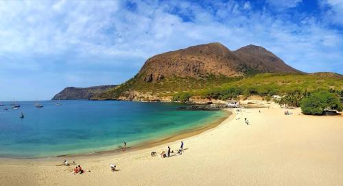 a group of people on a beach next to a mountain at Casa Cabral : Big Apartment next to the beach in Tarrafal