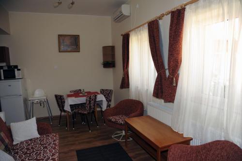 a living room with a table and chairs and a window at Arany Szőlő Wellness Apartmanház in Hévíz