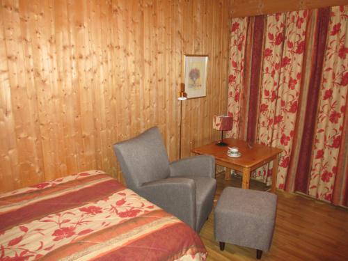 a bedroom with a bed and a chair and a table at Høvringen Fjellstue in Høvringen