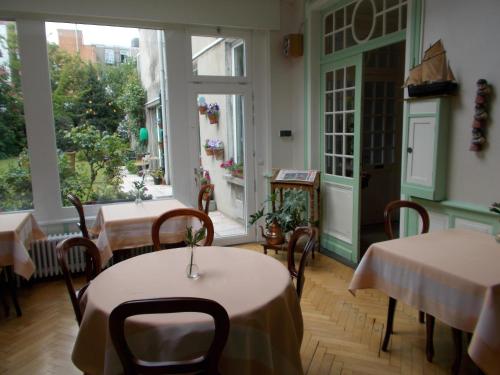 un restaurante con mesas, sillas y ventanas grandes en Hotel Manitoba, en Blankenberge