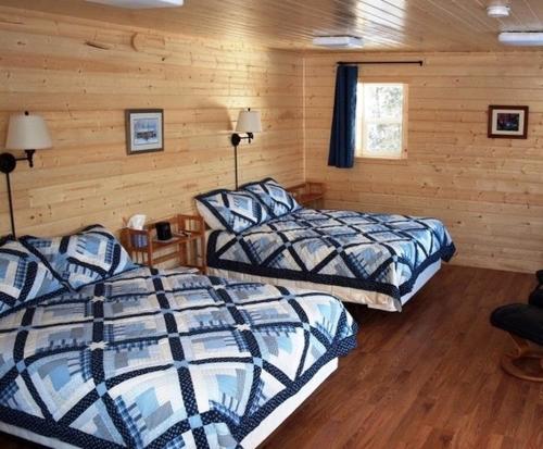 Duas camas num quarto com paredes de madeira em Talkeetna Lakeside Cabins em Talkeetna