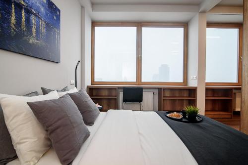 ein großes weißes Bett in einem Zimmer mit Fenstern in der Unterkunft Apartment with amazing view! in Vilnius