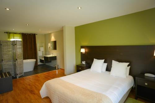 a bedroom with a large white bed and a bathroom at Logis Hôtel Restaurant l'Auberge Normande in Carentan