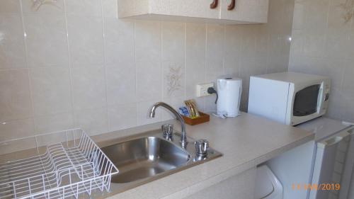 a kitchen counter with a sink and a microwave at Tower Court Motel - adults only haven in Hervey Bay
