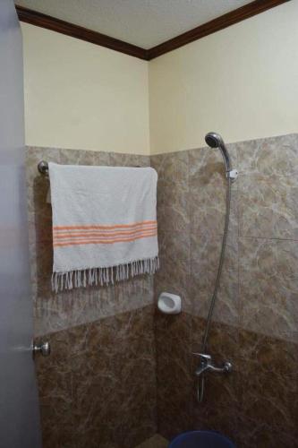 a bathroom with a shower with a towel on the wall at Bia's Beach House, Pagudpud in Pagudpud