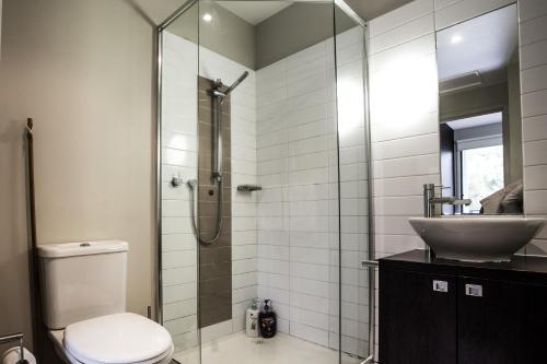 a bathroom with a shower and a toilet and a sink at ReadySet Apartments on Altona in Melbourne