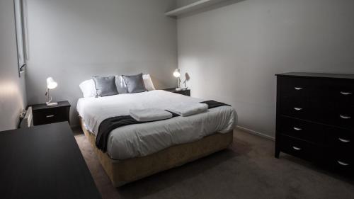 a bedroom with a large bed and a dresser at ReadySet Apartments on Altona in Melbourne