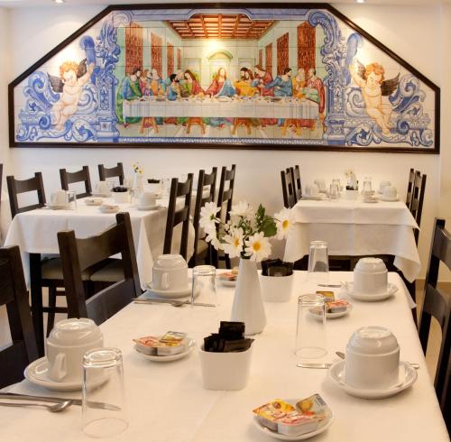 un restaurant avec des tables et des chaises blanches et une peinture murale dans l'établissement Residência S. Francisco, à Fátima