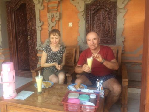 un hombre y una mujer sentados en un banco con bebidas en Arsa Homestay & Spa, en Ubud