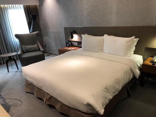 a hotel room with a large bed and a chair at CHECK inn Taipei Nanjing in Taipei