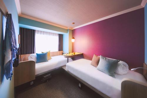 a room with two beds and a purple wall at OMO7 Asahikawa by Hoshino Resorts in Asahikawa