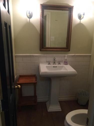 a bathroom with a sink and a mirror and a toilet at Niagara Mansion Carriage Suite in Lewiston