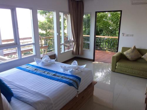 a bedroom with a bed and a couch and windows at HEAVEN HILL LANTA in Ko Lanta
