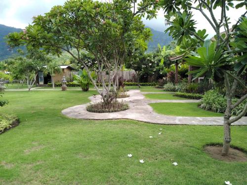 a garden with trees and a walk way at Krisna Homestay in Pemuteran