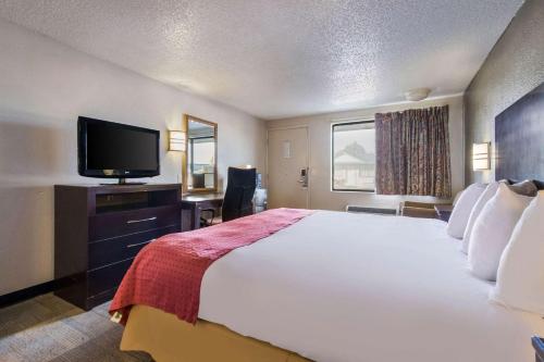 a hotel room with a large bed and a flat screen tv at Rodeway Inn Near Hall of Fame in Canton