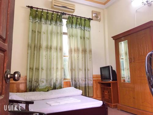 a room with a bed and a window with curtains at Vân Anh Guesthouse in Yên Bái